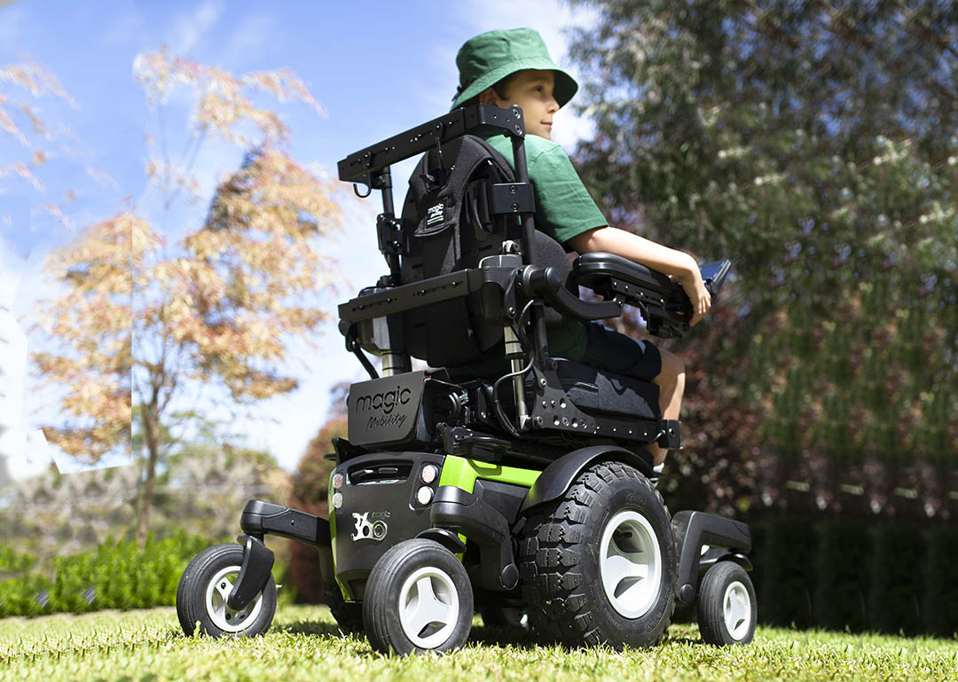 Magic Mobility M360 green with boy sitting in wheelchair