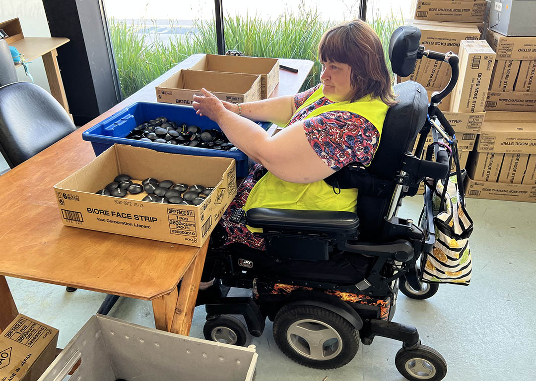 Bev tilts her Magic Mobility chair forward to work comfortably at her job.