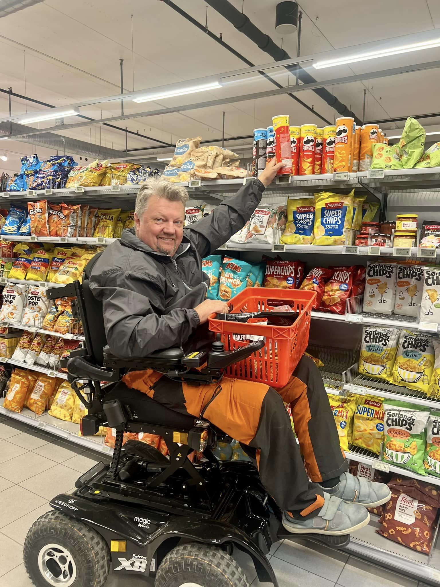 Wheelchair user in supermarket with elevated seat to reach higher shelf.